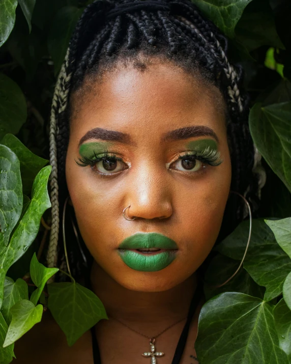 a woman with green lipstick standing near plants