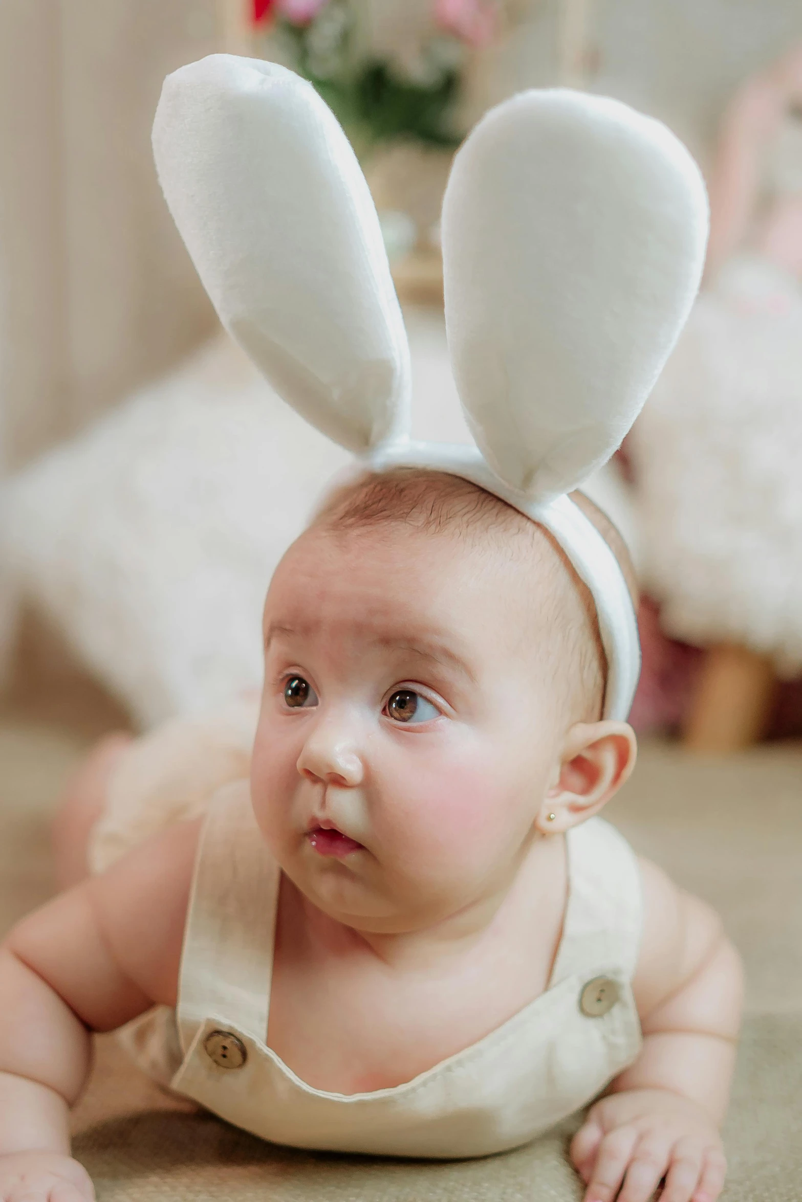 a baby laying on the floor wearing a white bunny hat