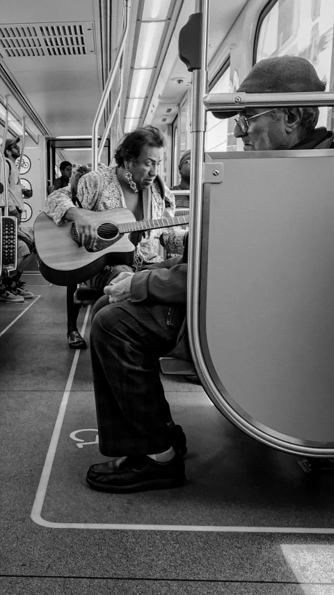 a man playing guitar on a commuter train