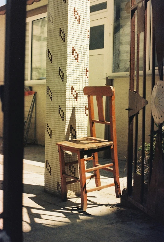 the chair is next to the tall brick wall