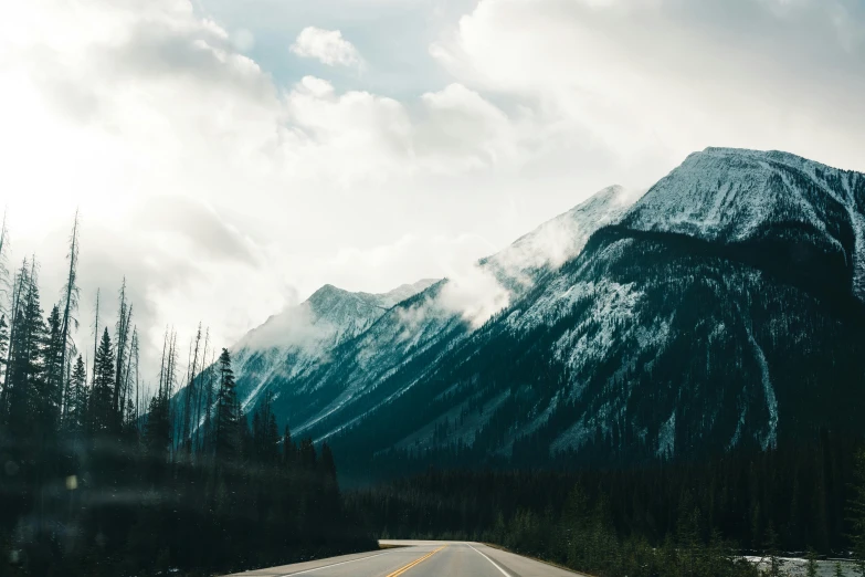 a snow capped mountain has clouds above it