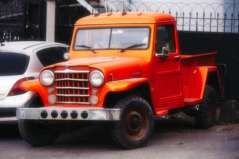 an orange and white truck is parked near a black fence