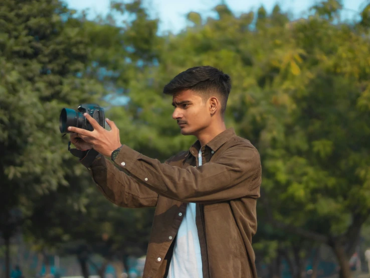 young man taking a picture with his camera on a sunny day