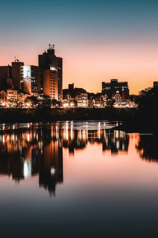 a sunset view of a city skyline and buildings across the river