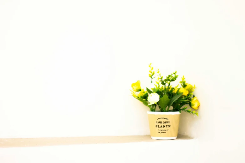 a cup with flowers in it sitting on top of a ledge