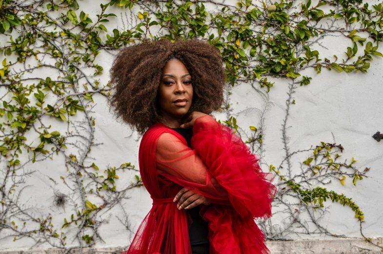 the woman has very long afro hair wearing a red dress