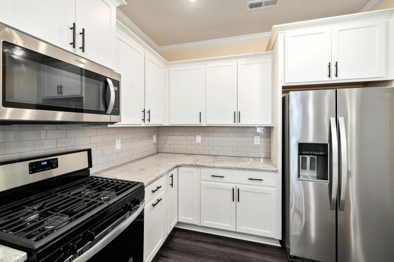 a kitchen with white cupboards and metallic appliances