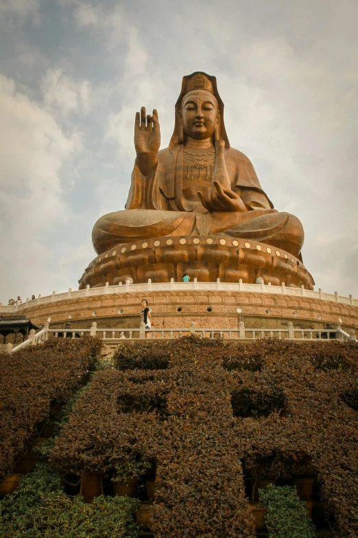 a large bronze buddha statue on a hill with greenery around it