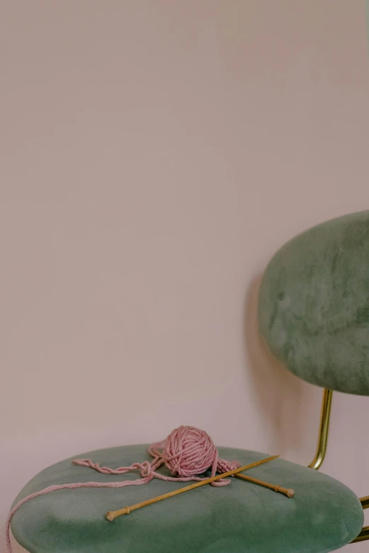 a chair is shown with a ball of yarn and knitting needles