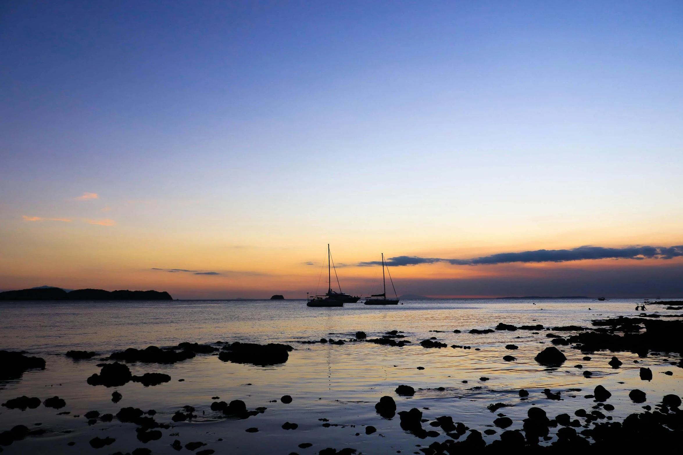 a lone sail boat sits on the beach