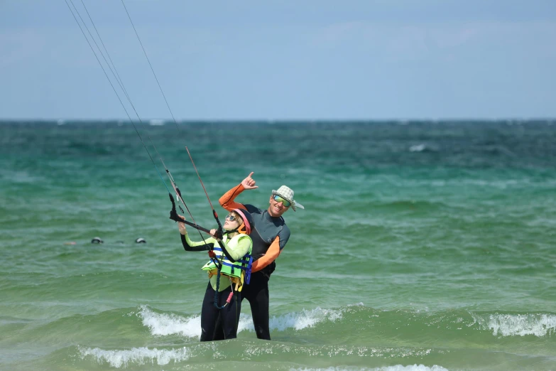 two people stand in the ocean holding strings