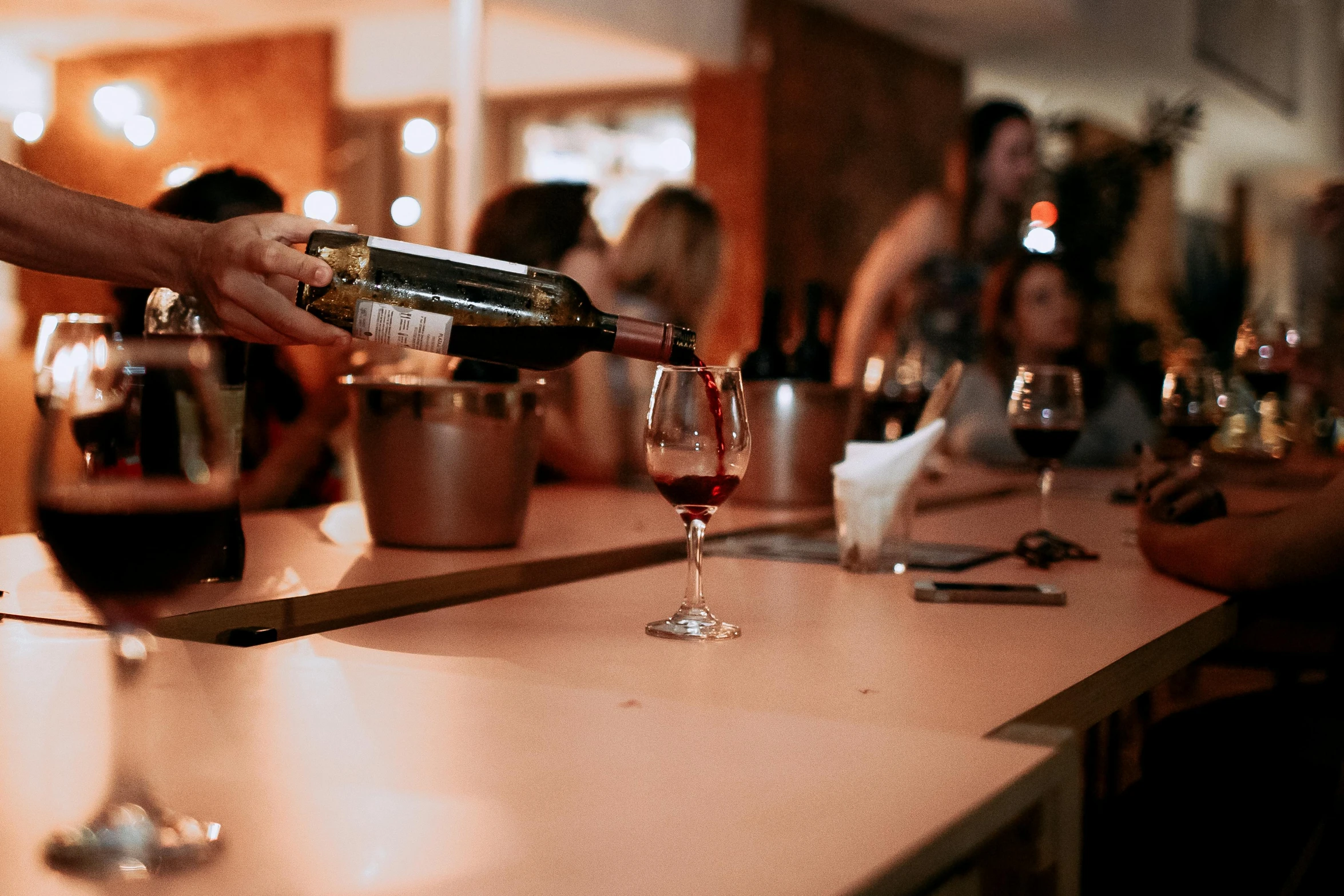 people sitting at tables with beverages being poured in a glass