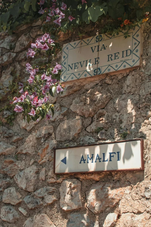 two signs hanging up on the side of a stone building