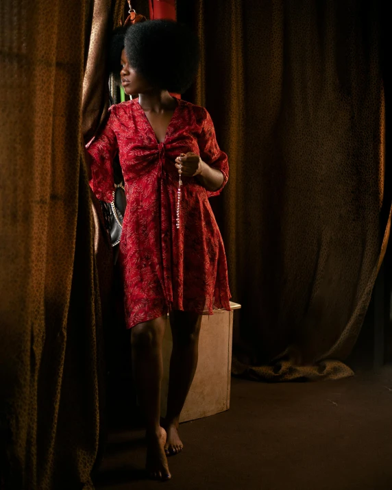 a woman wearing a red dress and holding a small bag