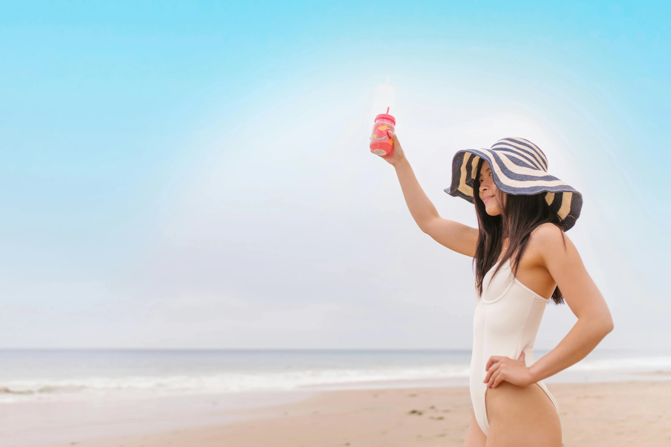 there is a woman that is at the beach holding a drink