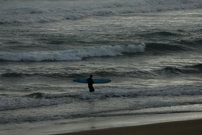 a man carrying a surfboard while walking into the ocean