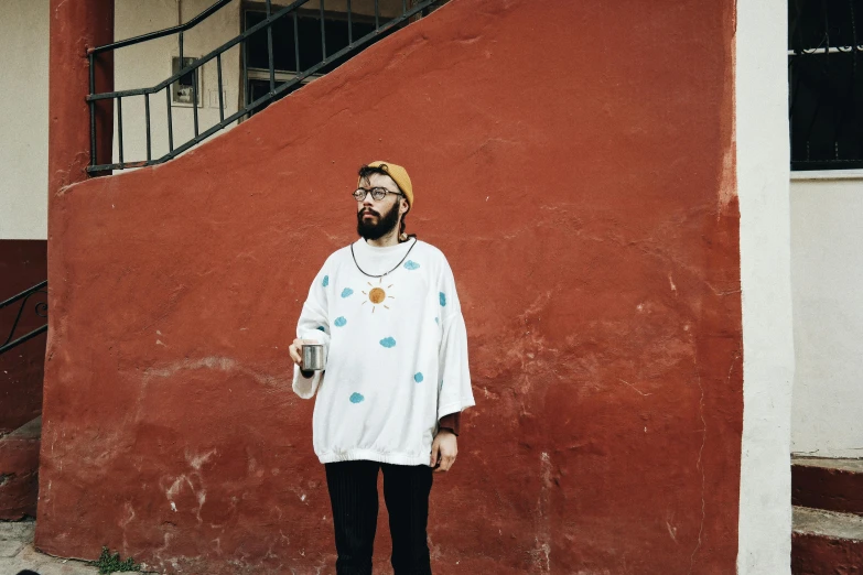 a man with a bottle standing next to a building