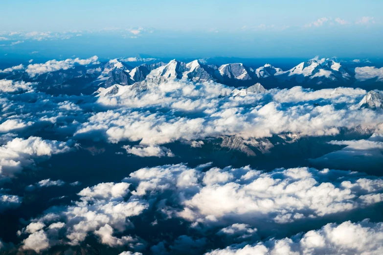an aerial view looking down on white fluffy clouds and a mountain range