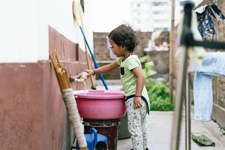 a child pouring out soing into a plastic bucket