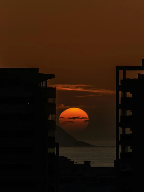 a sunset over the ocean with skyscrs silhouetted