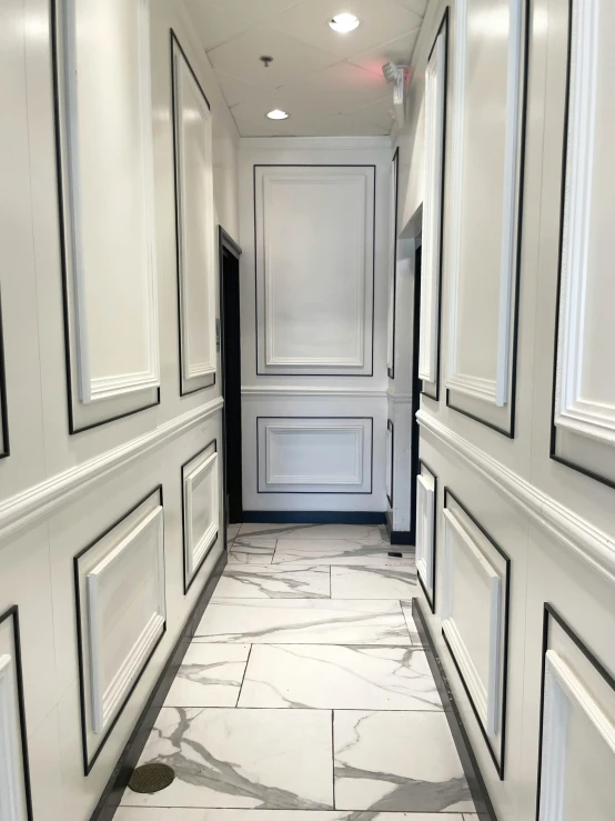 a long white corridor with marble tile flooring