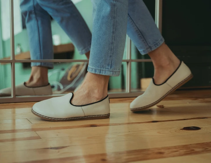 the bottom side of two legs of two people in slippers