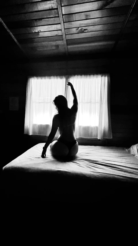 a woman stretching on a bed in a dark room