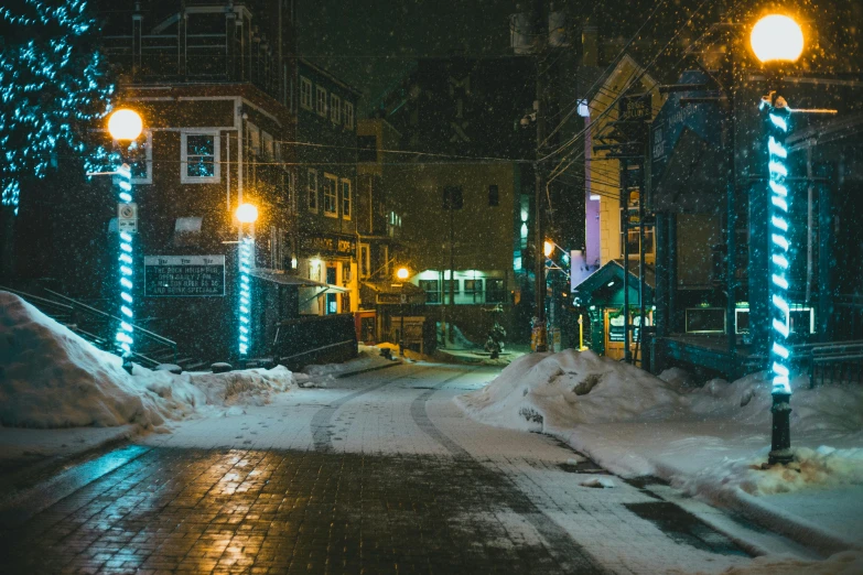 city street with lights on at night covered in snow