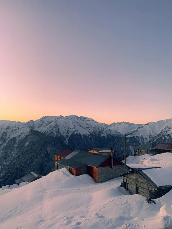 snowy mountains with houses and a ski lift at dusk