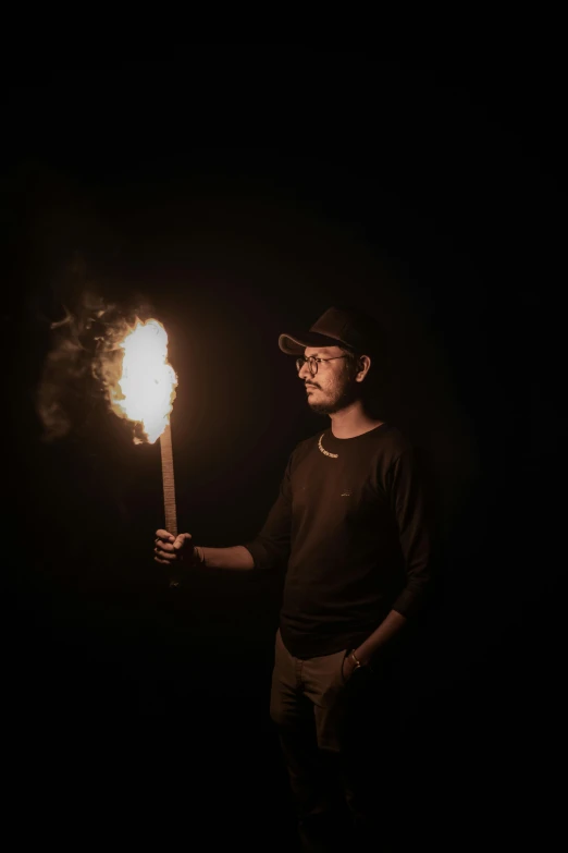 man in hat holding a fire stick in dark space