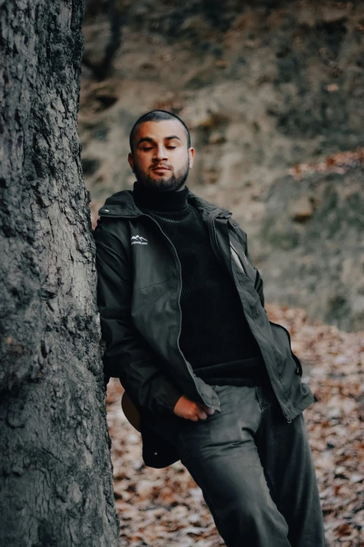 a young man leaning against a tree in the fall