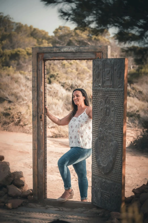 a woman posing in an opening of an arch in the dirt