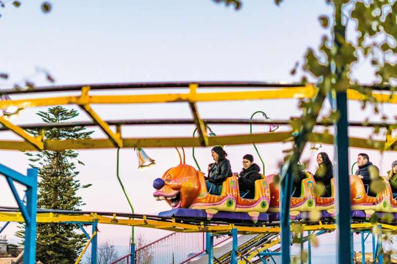 some people riding the roller coaster with people walking around