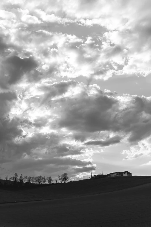 a black and white po of clouds over a hill