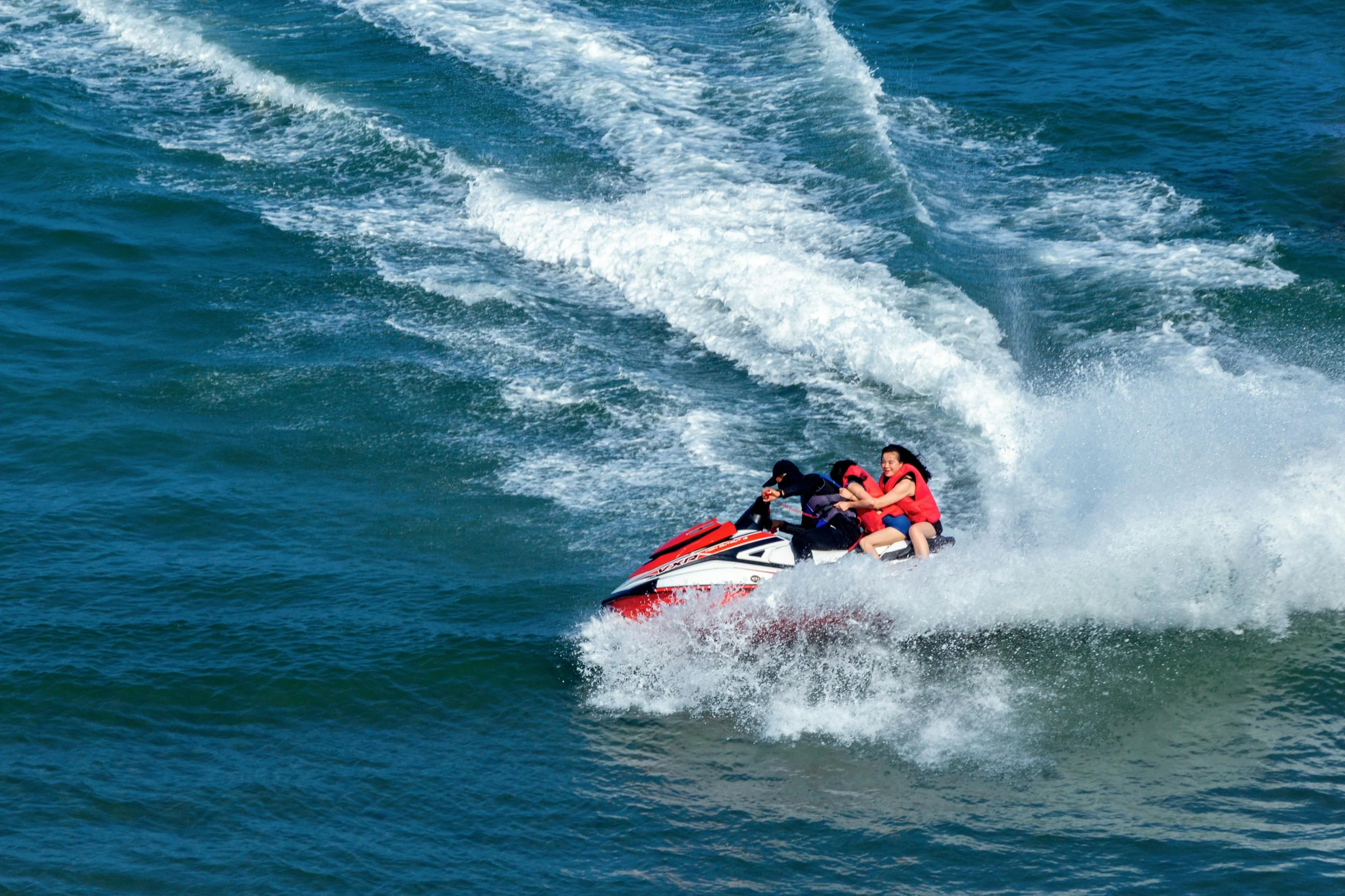 three people on a jet ski in the ocean