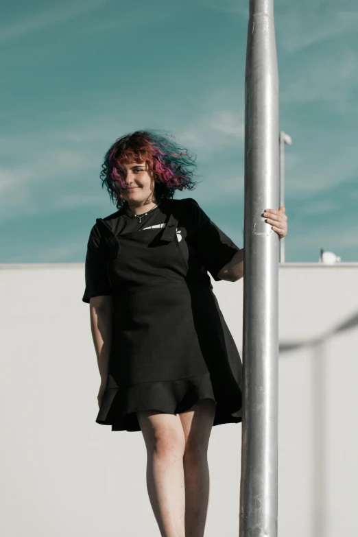 a woman with a pink hair standing under a street light