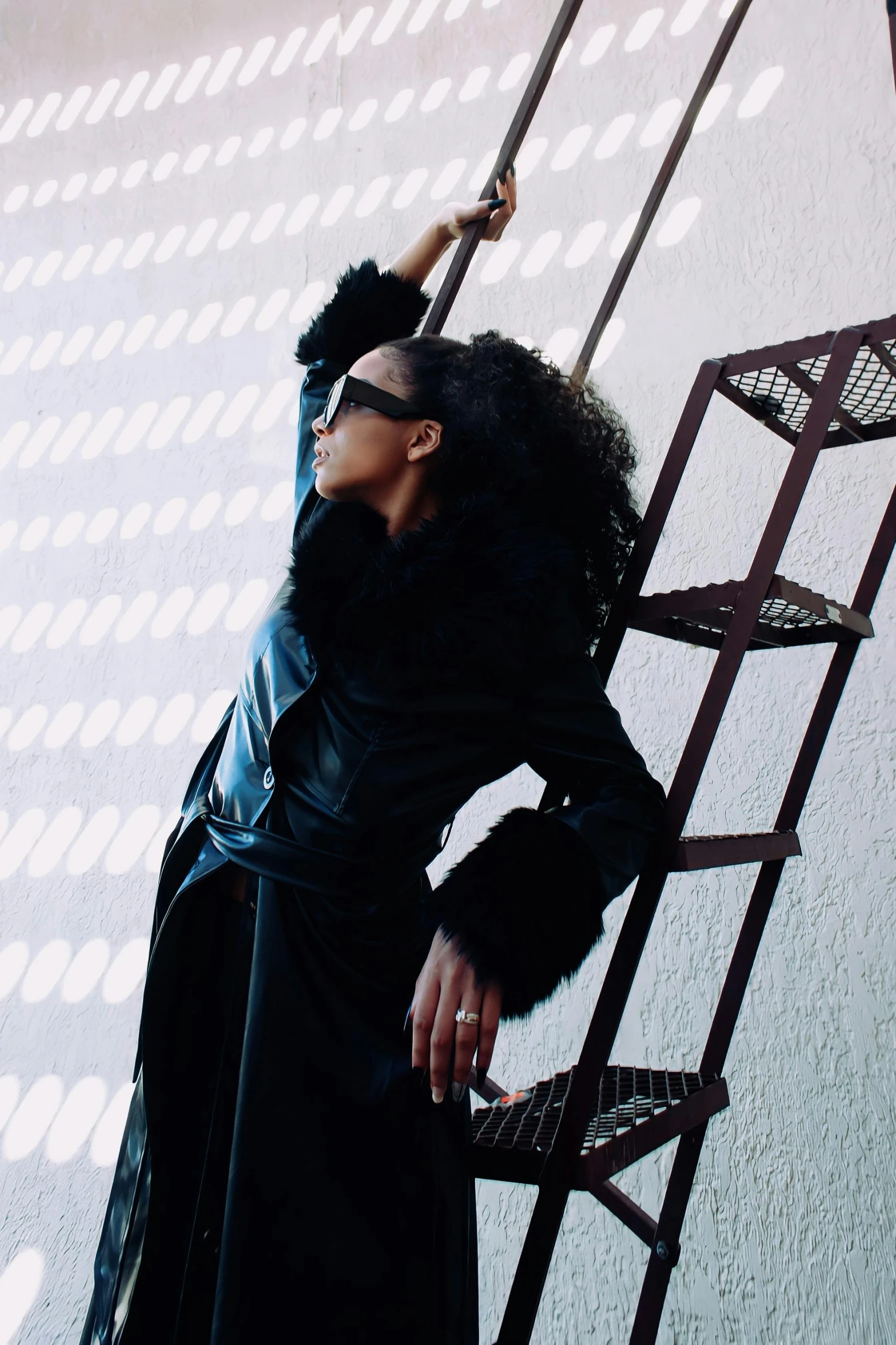 a woman in a black coat painting the wall with long brush