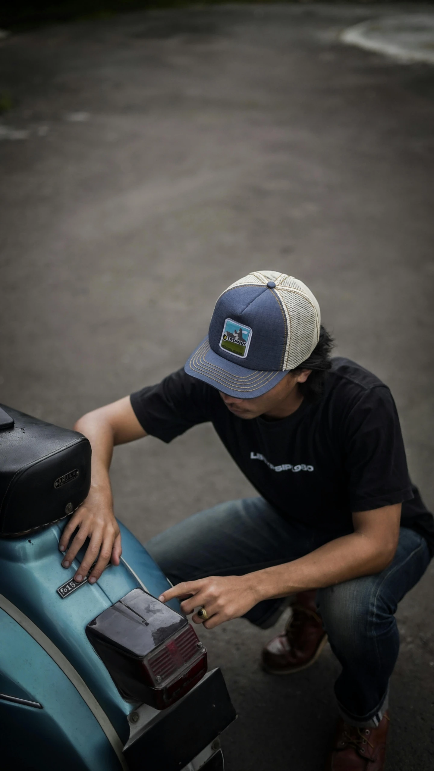 a man holding a blue scooter that is sitting on a street