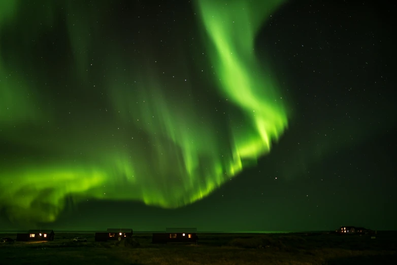 the northern lights and their silhouettes glow brightly over small houses