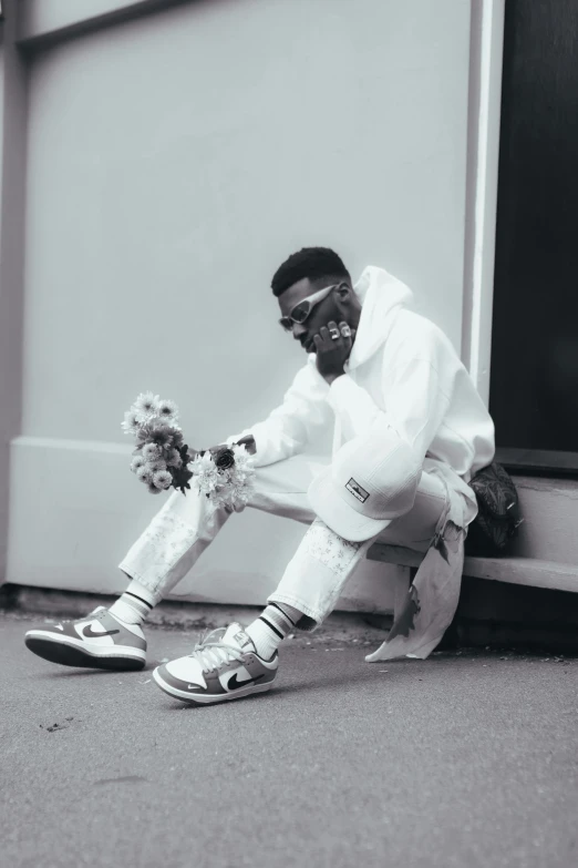 a young man in a white ensemble sitting on the ground