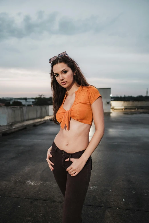a young woman in an orange crop top poses for a picture