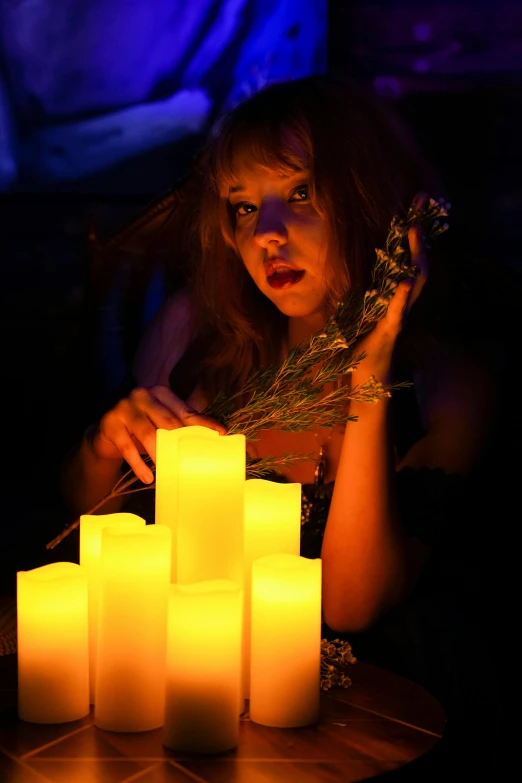 a woman holding a bunch of yellow candles in her hand