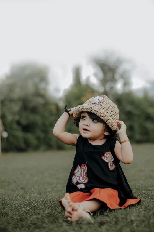 a toddler wearing a hat while sitting on the ground