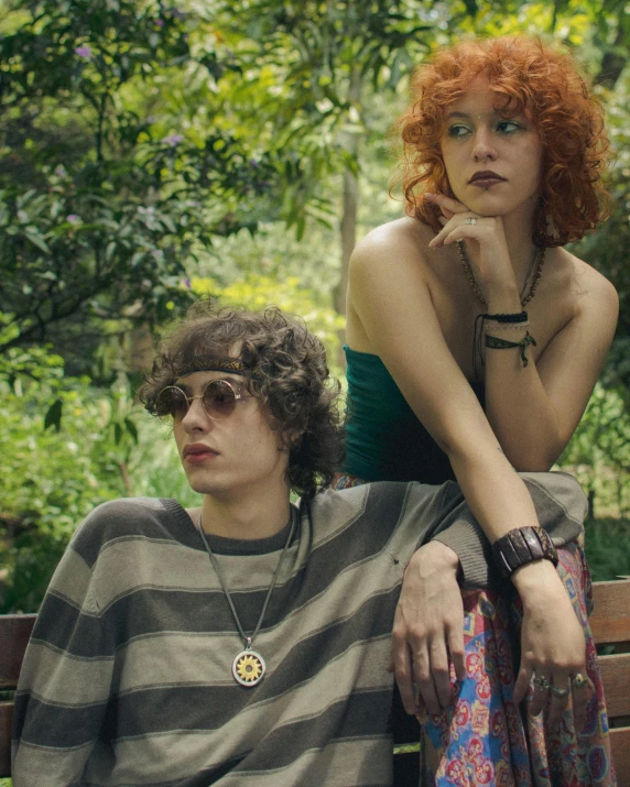 a man and woman pose on a park bench