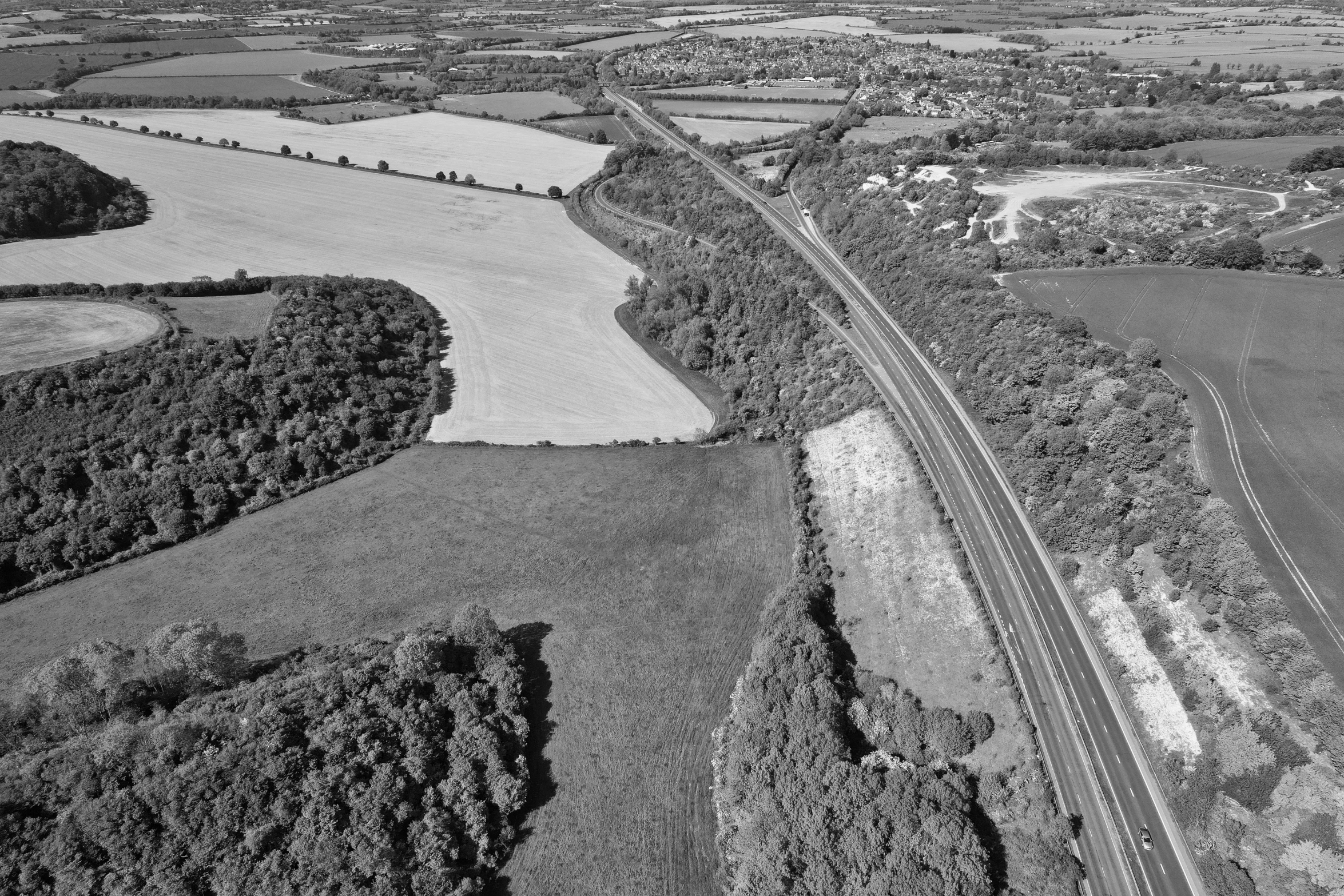 an aerial view of a highway surrounded by fields and forest