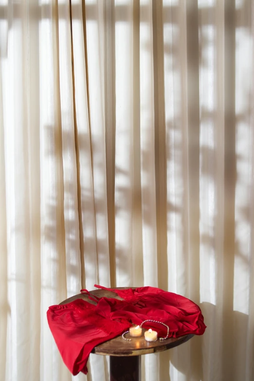 two candles on top of a table with curtains in the background