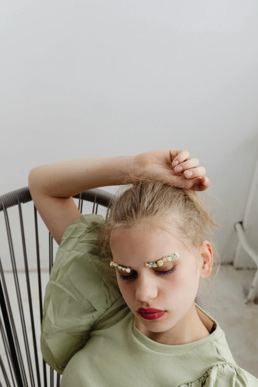 a girl with pink eyes and white eyelashes sitting in a black chair