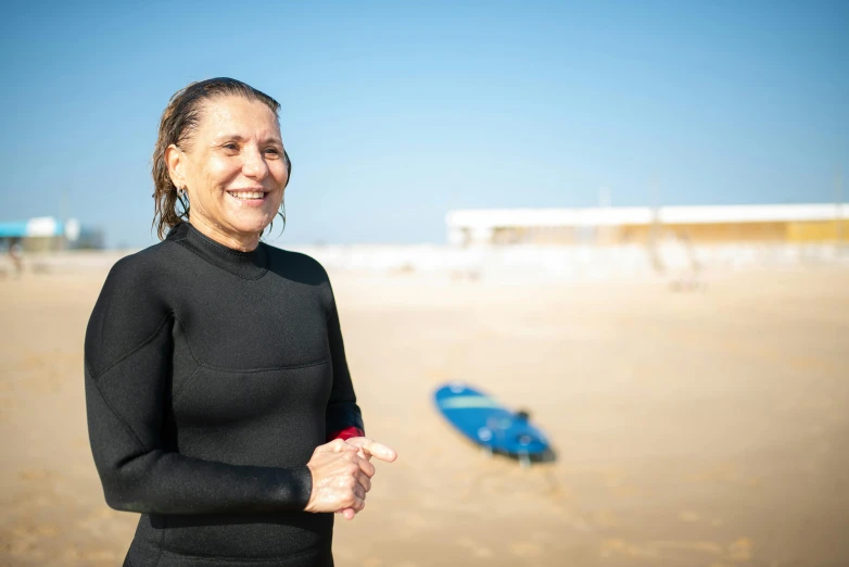 the woman smiles as she stands on a sandy beach