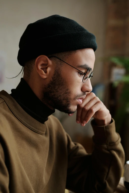 a man wearing glasses and a black hat looks at a computer screen