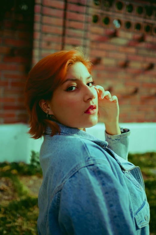 woman wearing denim jacket standing near brick wall